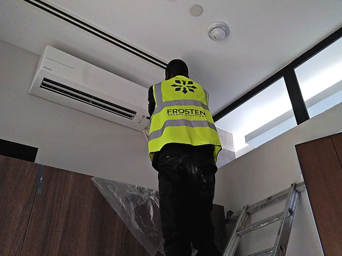 Frosten technician in branded hi-vis vest installing an indoor split unit